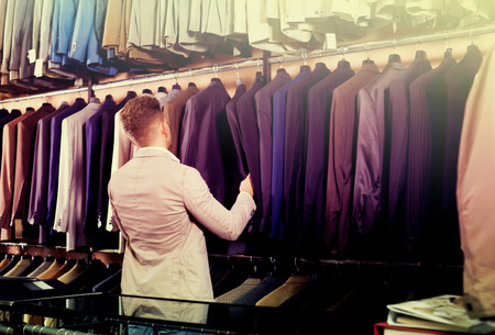 Positive guy deciding on new suit in mens cloths storeの写真素材