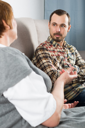 Smiling mother and adult son spending quality time together at homeの写真素材