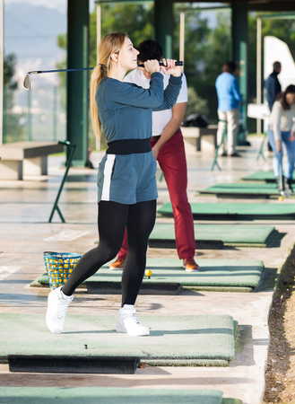 Young woman golfer propelled ball successfully at golf courseの写真素材
