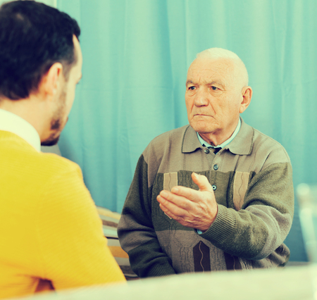 Mature father quarrelling with her adult son at homeの写真素材