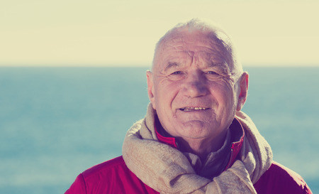 Mature smiling man walking by sea on sunny dayの写真素材