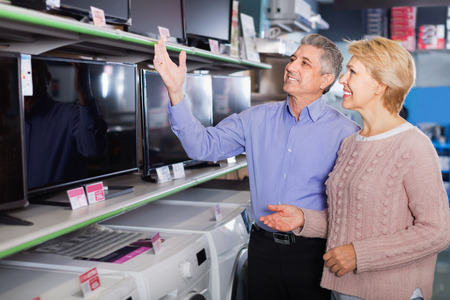 Glad cheerful positive mature couple buy in shop of household appliances TV for your houseの写真素材