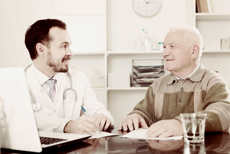 Old man visits doctor in hospital for consultation on health and treatmentの写真素材