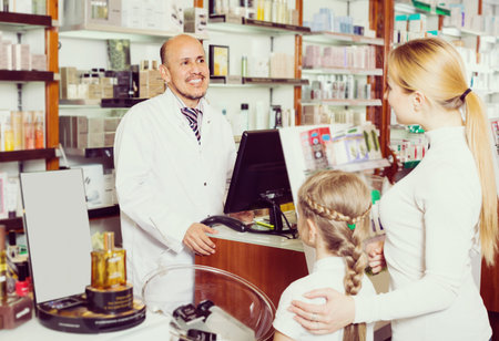 ?cheerful smiling pharmacist standing with a cash desk in the pharmacy and helping customersの写真素材