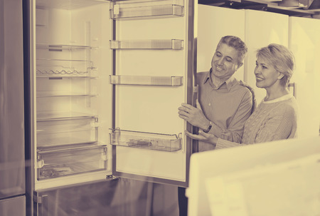 Husband and wife together in shop of household appliances are choosing refrigeratorの写真素材