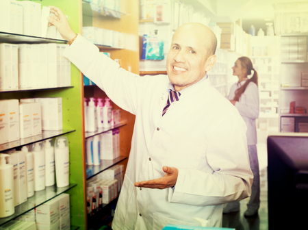 Portrait of friendly male pharmacist working in modern chemist shopの写真素材