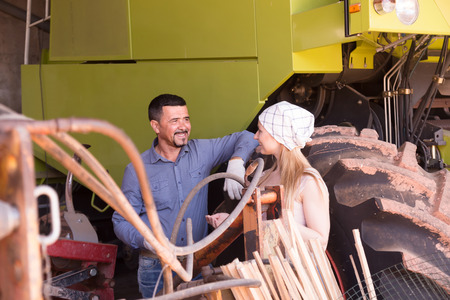 portrait of two joyful  farmers having a break and chatting close to huge tractorの写真素材