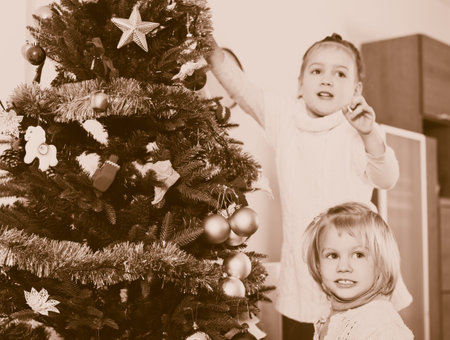 Little children together dress up Christmas tree indoor