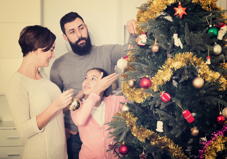 Young happy family decorating Christmas tree at homeの写真素材