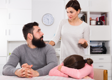 Young mother correcting her husband and child for disobedience at homeの写真素材