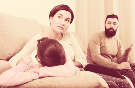 Young father lecturing his wife and daughter for disobedience at homeの写真素材