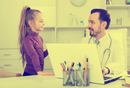Young female visitor consulting smiling man doctor in hospitalの写真素材