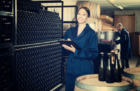 Young woman standing with cardboard on small winery manufacturingの写真素材