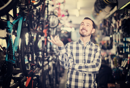 joyous man in bicycle shop chooses for himself sports bike from a rangeの写真素材