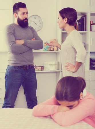 Father and mother quarrelling with each other while their daughter at homeの写真素材