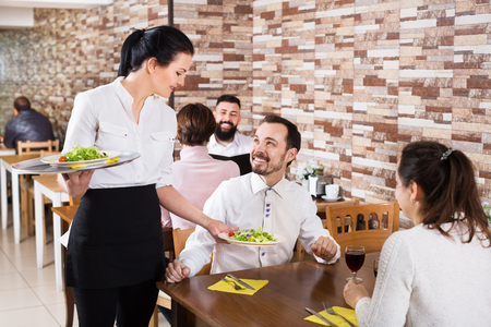 Positive waitress taking table order and smiling at a tavernの写真素材
