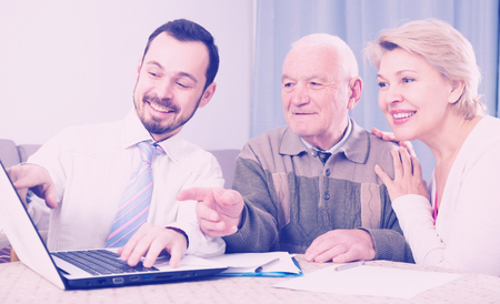 Mature woman and her eldery father studying agreement conditions with smiling managerの写真素材