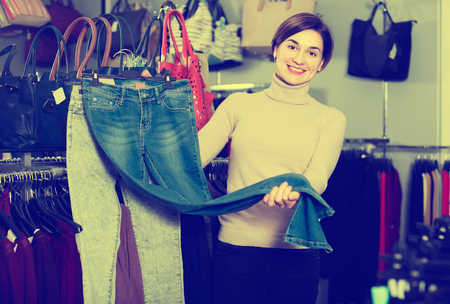 Woman demonstrates bought jeans in a clothing storeの写真素材