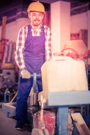 Young male worker is using gas saw for construction work at workshop.の写真素材