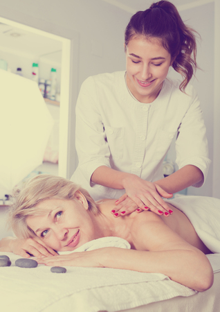 Senior beautiful woman having professional massage in spa salonの写真素材