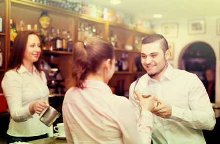 Small romantic  bar with female barista and two clients at counter