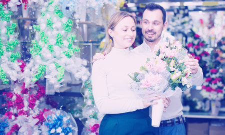 Young man buys a bouquet of flowers to a girl in a flower shopの写真素材