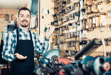 Adult man worker displaying his tools for making keys in workshopの写真素材