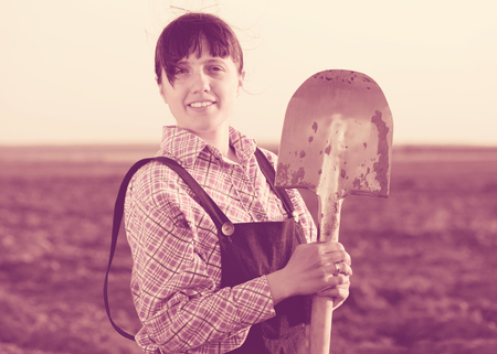 Happy female farmer  with shovel in fieldの写真素材