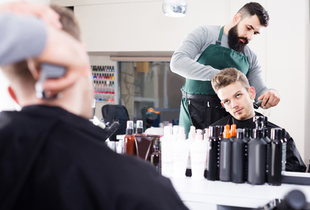 Young english client feeling discontent about his new haircut at hair salonの写真素材