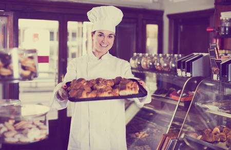 Smiling pastry maker demonstrating fresh delicious croissants in confectioneryの写真素材