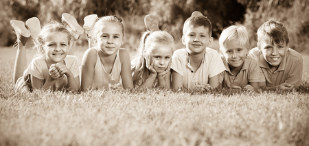 smiling kids lying on green grass on bright summer dayの写真素材