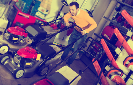 Glad man choosing lawnmower in garden equipment shopの写真素材