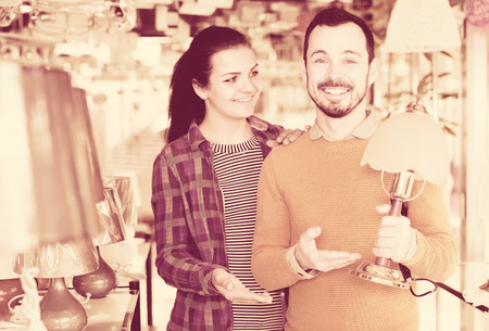 Young guy and a girl choose a table lamp in a light storeの写真素材