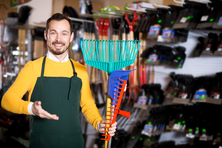 Glad man seller displaying various items in garden equipment shopの写真素材
