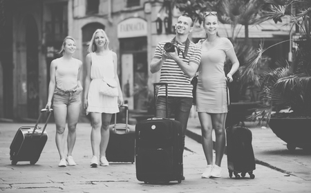 Positive smiling man and woman tourists holding camera in hands and photographing in cityの写真素材