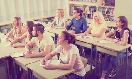 Students in university classroom are sitting at their desks and looking forward at professorの写真素材