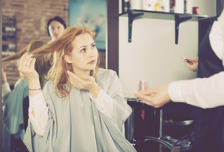 Dissatisfied woman is upset by her haircut and master in hairdress salonの写真素材