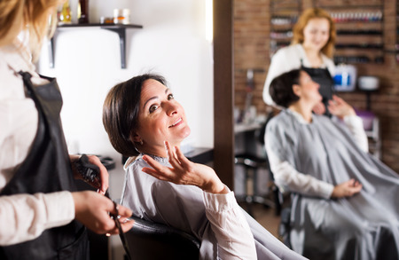 Smiling woman happy with her haircut and young hairdresser in hairdress salonの写真素材