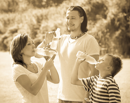 Happy ordinary  couple with teenager drinking water from  bottlesの写真素材