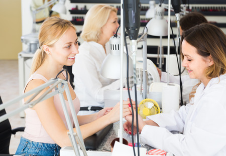 Two positive women doing manicure in nail salonの写真素材