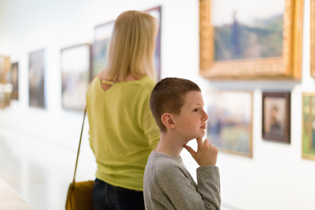Smiling glad mother and son regarding paintings in halls of museumの写真素材