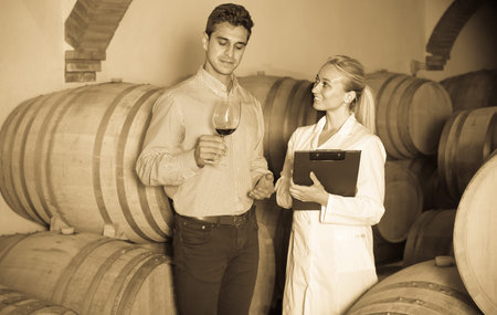 Male owner of winery talking with technician in cellarの写真素材