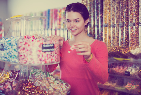 Happy brunette girl buying candies at shopの写真素材