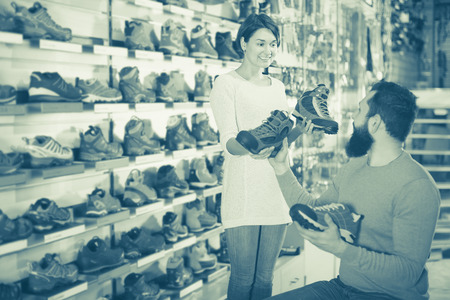 Young family couple choosing new sneakers in sports equipment storeの写真素材