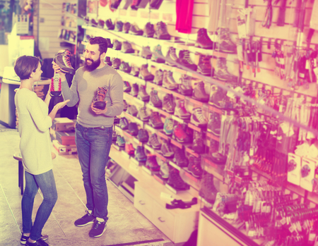 Young couple selecting new sneakers in sports equipment shopの写真素材