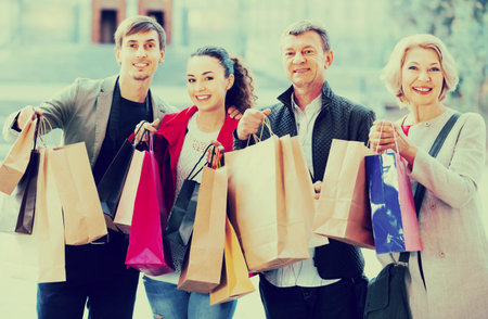 Glad family of four with shopping bags on city street
