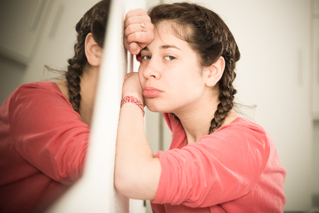 Young girl feeling distressed and lonely alone at homeの写真素材