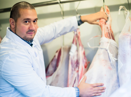 Male shop staff cutting fresh sirloin at top for sellingの写真素材