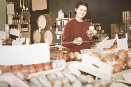 portrait of happy english  young customer selecting apple in groceryの写真素材