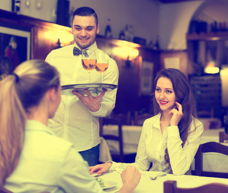 Two young women eating salads and drinking wine in a rural restaurantの写真素材